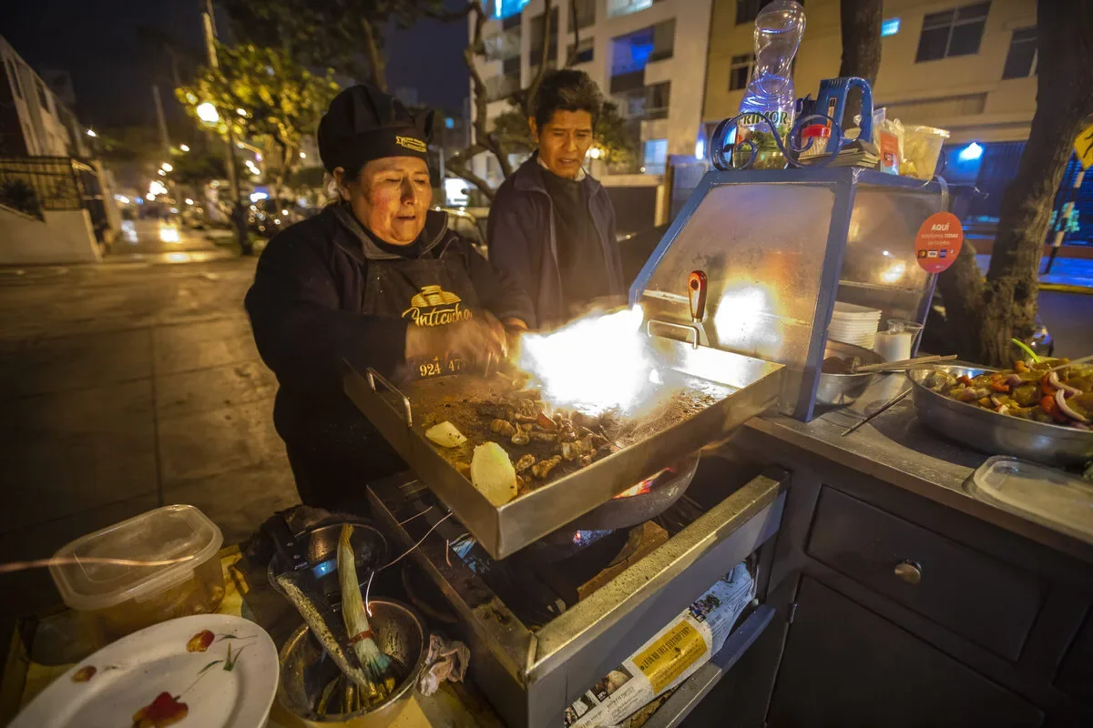 Lima street food stall serving anticuchos and picarones for backpackers.