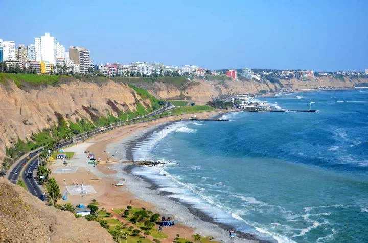 Surfers enjoying waves on a sunny day at Lima’s best nearby beaches.