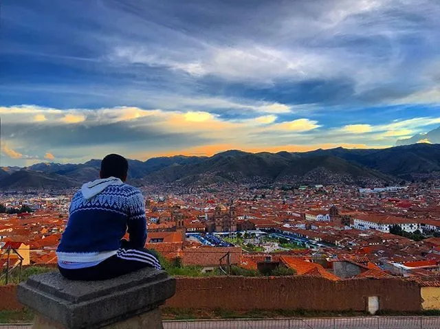Backpacker admiring the sunset view of Cusco city.